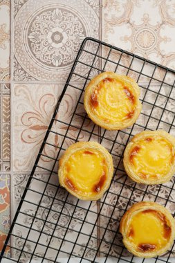 Geleneksel Portekiz vanilyalı puding puf puf böreği pastel de nata üzerinde siyah fırın rafı üzerinde pembe fayanslar arka plan - üst görünüm