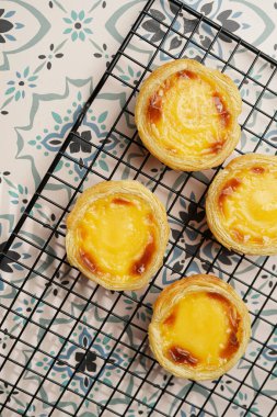 Geleneksel Portekiz vanilyalı puding puf puf böreği pastel de nata üzerinde siyah fırın rafı mavi karo arka plan - üst görünüm