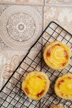 Geleneksel Portekiz vanilyalı puding puf puf böreği pastel de nata üzerinde siyah fırın rafı üzerinde pembe fayanslar arka plan - üst görünüm