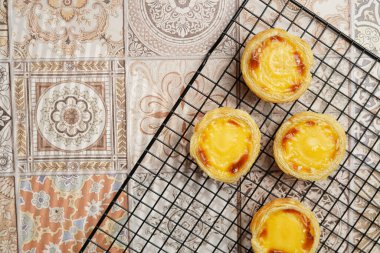 Geleneksel Portekiz vanilyalı puding puf puf böreği pastel de nata üzerinde siyah fırın rafı üzerinde pembe fayanslar arka plan - üst görünüm