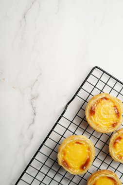 Geleneksel Portekiz vanilyalı puding puf puf pastası siyah fırın rafında mermer zemin - üst görünüm, kopyalama alanı