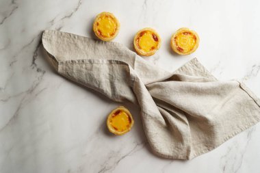 Geleneksel Portekiz vanilyalı puf puf böreği mermer zemin üzerinde pastel de nata keten mutfak havlusu