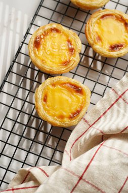 Geleneksel Portekiz vanilyalı puding puf puf pastası siyah fırın rafında mermer arka planda kareli mutfak havlusu