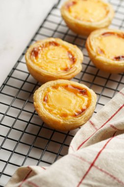 Geleneksel Portekiz vanilyalı puding puf puf pastası siyah fırın rafında mermer arka planda kareli mutfak havlusu