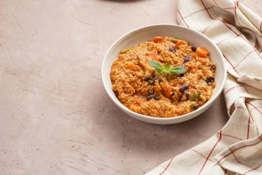 Tahıl tabağı - Millet domatesli, fasulyeli, havuçlu ve baharatlı, beyaz bir kasede naneli ve mor arka planda keten havlusu olan