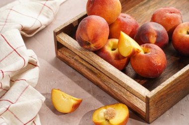 Bir sürü bütün ve dilimlenmiş şeftaliler ahşap sepetin içinde mor arka planda