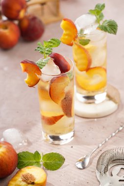 Buzlu, şeftali dilimli ve soluk mor arkaplanlı taze naneli ferahlatıcı yaz kokteyli.