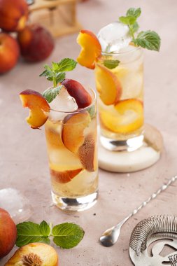 Buzlu, şeftali dilimli ve soluk mor arkaplanlı taze naneli ferahlatıcı yaz kokteyli.