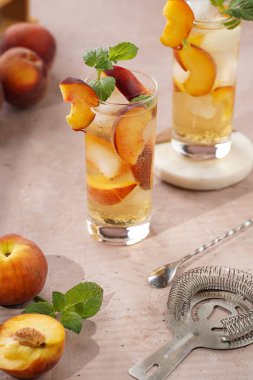 Buzlu, şeftali dilimli ve soluk mor arkaplanlı taze naneli ferahlatıcı yaz kokteyli.