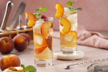 Buzlu, şeftali dilimli ve soluk mor arkaplanlı taze naneli ferahlatıcı yaz kokteyli.