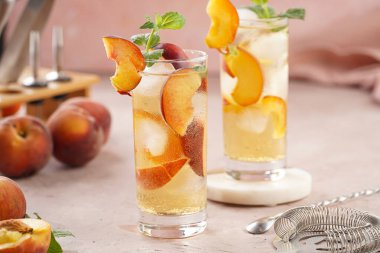 Buzlu, şeftali dilimli ve soluk mor arkaplanlı taze naneli ferahlatıcı yaz kokteyli.