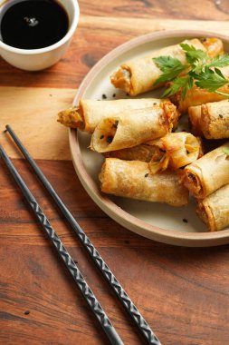 Geleneksel Güneydoğu Asya başlangıç yemeği bahar ya da yaz börekleri - soya soslu bol kızarmış Dim Sum köftesi, siyah pirzola çubuklarıyla gri tabakta taze kişniş, ahşap