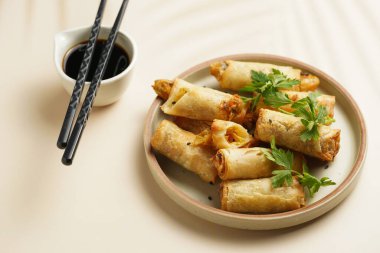 Geleneksel Güneydoğu Asya başlangıç yemeği bahar ya da yaz börekleri - soya soslu bol kızarmış Dim Sum köftesi, gri tabakta siyah pirzola çubuklarıyla taze kişniş.