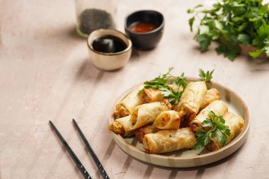 Geleneksel Güneydoğu Asya başlangıç yemeği bahar ya da yaz börekleri - soya soslu bol kızarmış Dim Sum köftesi, gri tabakta siyah pirzola çubuklarıyla taze kişniş.