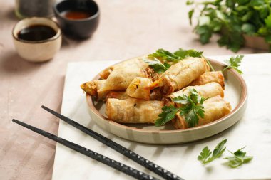 Geleneksel Güneydoğu Asya başlangıç yemeği bahar ya da yaz börekleri - soya soslu bol kızarmış Dim Sum köftesi, gri tabakta siyah pirzola çubuklarıyla taze kişniş.