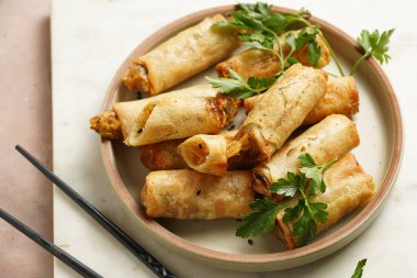 Geleneksel Güneydoğu Asya başlangıç yemeği bahar ya da yaz börekleri - soya soslu bol kızarmış Dim Sum köftesi, gri tabakta siyah pirzola çubuklarıyla taze kişniş.