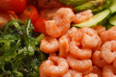 Modaya uygun erdem tabağı ya da Buda kasesi - pirinç, wakame yosunu, domates, salatalık ve kırmızı balık somonu - yakın plan karides.