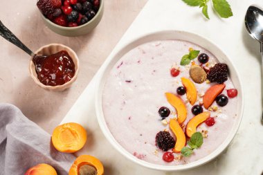 Geleneksel kahvaltı irmik lapası - kayısı dilimli mor kremalı puding, donmuş böğürtlen, taze nane, mermer tahtada reçel