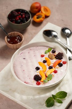 Geleneksel kahvaltı irmik lapası - kayısı dilimli mor kremalı puding, donmuş böğürtlen, taze nane, mermer tahtada reçel
