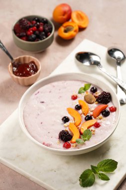 Geleneksel kahvaltı irmik lapası - kayısı dilimli mor kremalı puding, donmuş böğürtlen, taze nane, mermer tahtada reçel