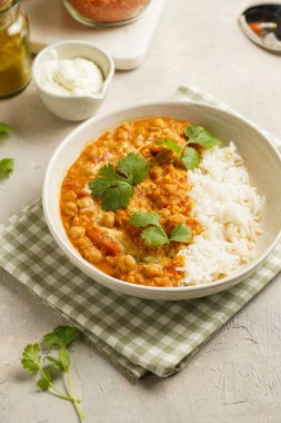 Hint kırmızı mercimeği, nohut, beyaz pirinç ve taze kişniş - chana dal ile yeşil kareli mutfak havlusunda beyaz bir kasede.