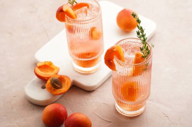 Buz küpleri, kayısı dilimleri ve soluk mor arka planda mermer tahtada taze kekik ile ferahlatıcı yaz kokteyli.