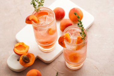 Buz küpleri, kayısı dilimleri ve soluk mor arka planda mermer tahtada taze kekik ile ferahlatıcı yaz kokteyli.