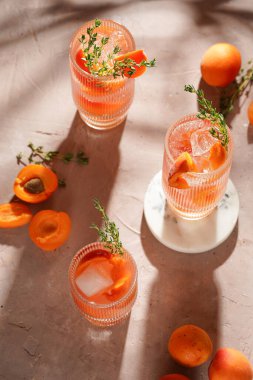 Buz küpleri, kayısı dilimleri ve soluk mor arka planda mermer tahtada taze kekik ile ferahlatıcı yaz kokteyli.