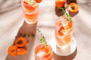 Buz küpleri, kayısı dilimleri ve soluk mor arka planda mermer tahtada taze kekik ile ferahlatıcı yaz kokteyli.