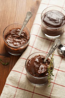 Kremalı Fransız çikolatalı ganache ya da cam içinde puding ahşap arka planda keten peçete, üç bardak