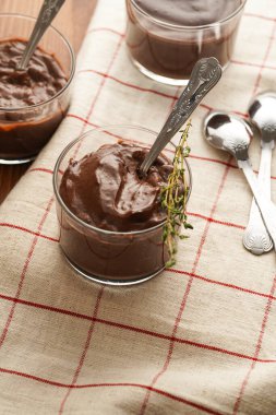 Kremalı Fransız çikolatalı ganache ya da cam içinde puding ahşap arka planda keten peçete, üç bardak