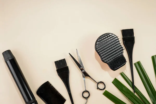 Hair brushes and combs, scissors, cosmetics for hair dying: tools for hairdresser on beige colored background arranged as a side frame, a template, space for text