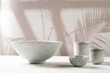 Empty grey ceramic scandy soup bowl, espresso coffee mugs and dip bowl, fork and knife on a marble surface and kitchen towel