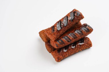 Geleneksel Güney Avrupa derisiz sosisleri kıyma ve baharattan yapılmıştır, soya proteininden yapılmış vejetaryen yedeği, beyaz arka planda istiflenmiştir.