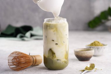 Buzlu büyük boba çay bardağına süt dökmek, matcha latte yapmak için kibrit yeşil çay.