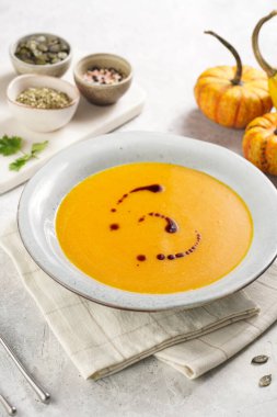 Koyu gri bir çorba kasesi turuncu kabak kremalı çorba kabak tohumu yağlı gri bir arka planda