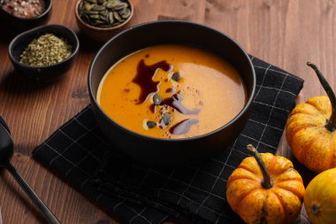 Turuncu kabak kremalı koyu siyah bir kase kabak tohumu yağlı, ahşap bir yüzeyde iki siyah kaşık