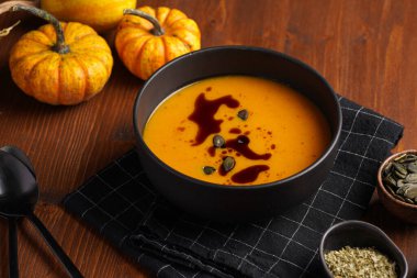 Turuncu kabak kremalı koyu siyah bir kase kabak tohumu yağlı, ahşap bir yüzeyde iki siyah kaşık