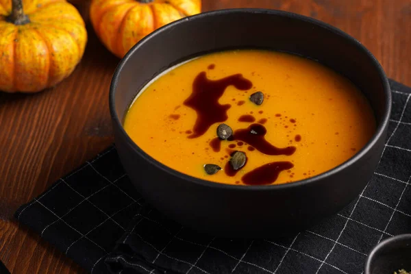 Eine Tiefschwarze Schüssel Mit Einer Orangen Kürbiscremesuppe Mit Kürbiskernöl Zwei — Stockfoto