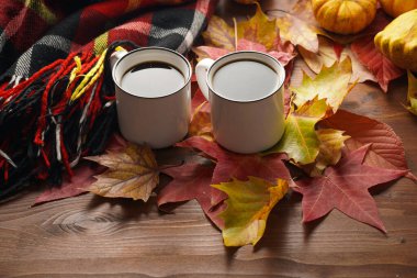 Kırmızı, sarı ve turuncu yapraklı, ahşap arka planda hokkaido balkabaklı, sade bir sonbahar mevsiminde sade kahve.