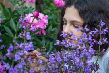 girl in the garden near the peony and sage bushes