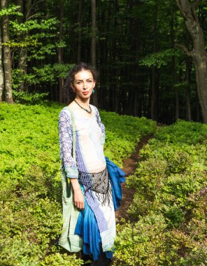 Genç esmer kadın Karpatya ormanlarında bir yolda, yaz, Ukrayna, boho tarzı kıyafetler