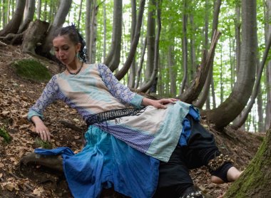 Yazın Ukrayna 'da Kayın Karpat Ormanı' ndaki bir ağacın yanında boho elbiseli esmer bir kadın.