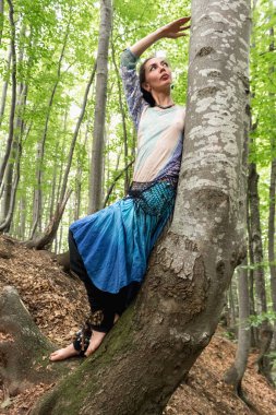 Yazın Ukrayna 'da Kayın Karpat Ormanı' ndaki bir ağacın yanında boho elbiseli esmer bir kadın.
