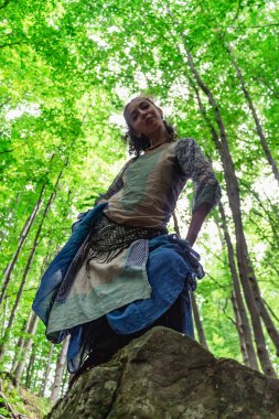 Esmer kadın ormanda bir taşın üzerinde duruyor, yaz, Ukraynalı Karpatyalı.