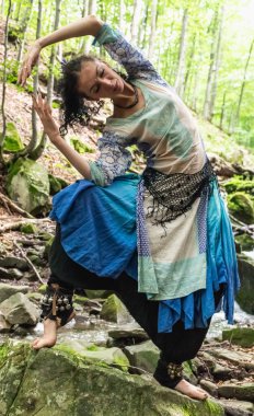 Mavi elbiseli esmer kadın bir dağ deresinin yanında duruyor, Ukrain.