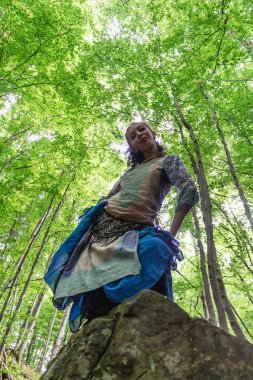 Esmer kadın ormanda bir taşın üzerinde duruyor, yaz, Ukraynalı Karpatyalı.