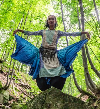 Esmer kadın ormanda bir taşın üzerinde duruyor, yaz, Ukraynalı Karpatyalı.