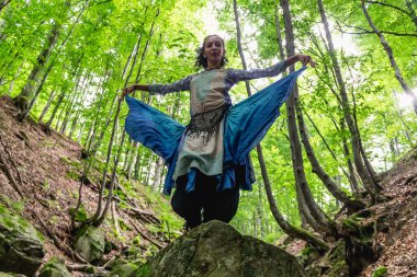 Esmer kadın ormanda bir taşın üzerinde duruyor, yaz, Ukraynalı Karpatyalı.