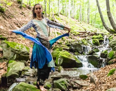 Dere kenarında dans eden esmer kadın, mavi kıyafetler, yaz, Karpatyalı.